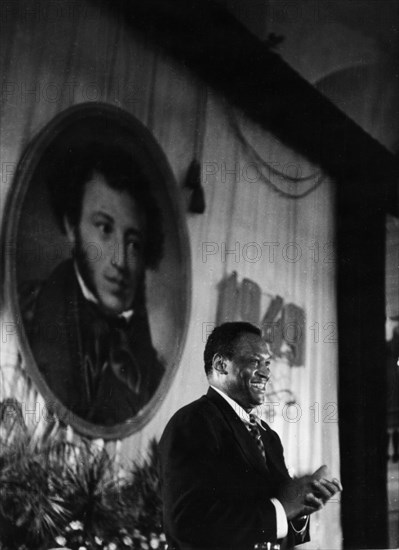American singer paul robeson speaking in front of a portrait of pushkin at the hall of columns of the house of trade unions in moscow during the celebrations of the 150th anniversary of the poet's birth, june 1949.