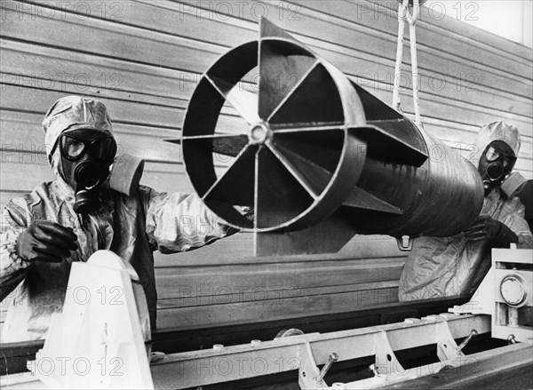 Technicians in protective suits lift empty case of chemical air bomb out of a discharge chamber after the chemical agent was drained,  soviet military base of shikhany, saratov region, ussr, october 4th 1987, diplomats and military experts from 45 countries witnessed a mass decommiss-ioning of chemical weapons.