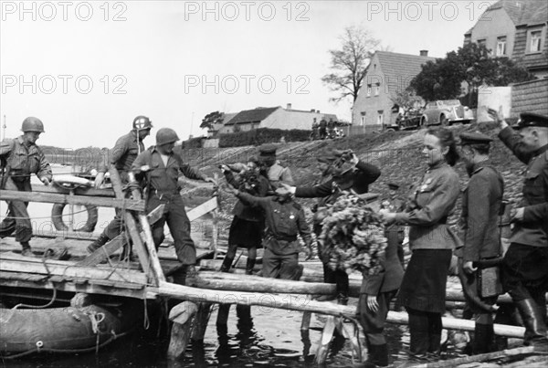 Soviet red army troops meeting the troops of the 1st american army as they cross the elba river near torgau, germany on april 25, 1945.