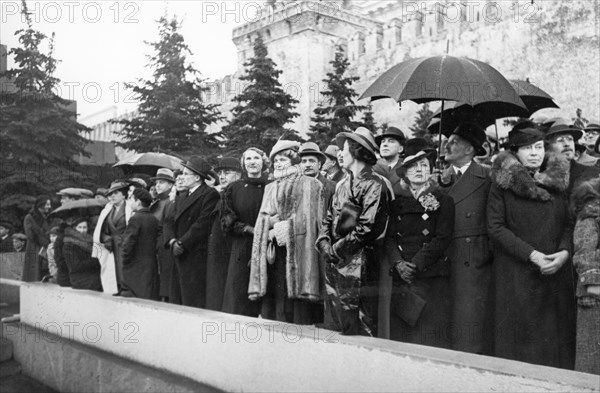 Members of the diplomatic corps with friends and family in red square, watching a demonstration, mrs, joseph davies, wife of the american ambassador to the ussr, is in the center (w/ light hat & cape), 1930s.
