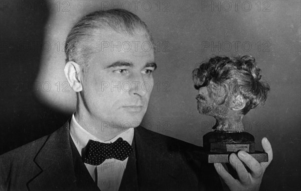 Nuremberg war crimes trial, world war 2, american prosecutor thomas j, dodd holding a shrunken head that decorated the desk of the chief of the buchenwald death camp, head of a male concentration camp victim who was hanged and then beheaded, international war tribunal.
