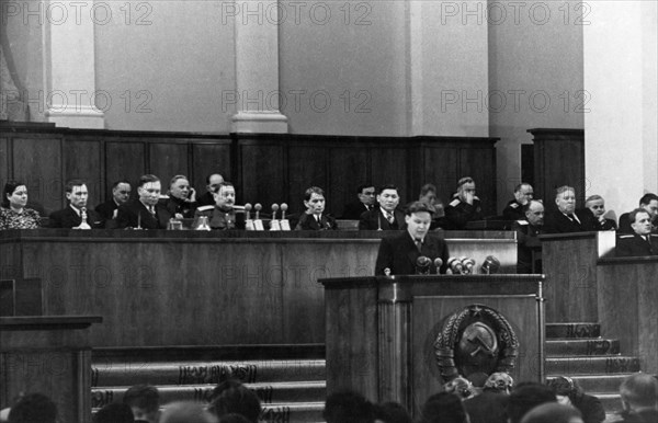 Nikolai alekseyevich voznesensky, chairman of the state planning commission of the ussr, speaking at the joint session of the supreme soviet of the ussr and the soviet of nationalities, seated behind him on the presidium are (l to r): ch, aslanova and p, levitsky, vice-chairmen of the soviet of nationalities, a, zhdanov, chairman of the soviet of the union, t, lysenko and n, undasynov, vice-chairmen of the soviet of the union.