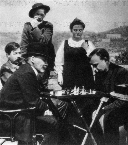 V,i, lenin (in bowler hat) plays chess with a, a, bogdanov while visiting a,m, gorky (in background, in wide-brimmed hat, standing next to natalya bogdanova), zinovll peshkov, who was standing behind them, has been edited out of this version of the photo, capri, italy, april 1908.