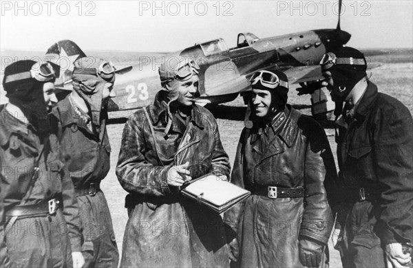 World war 2, soviet pilots commanded by gusarov (center) who shot down 15 enemy planes during aerial combat near kharkov in the six day period between may 11 aqnd17, a soviet air force yakovlev yak-7 (?) fighter is in the background.