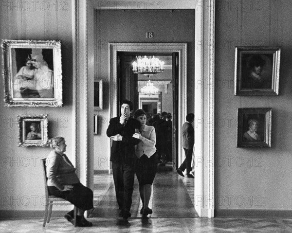 A young russian couple walk through the halls of a moscow museum, art gallery, ussr, 1960s.
