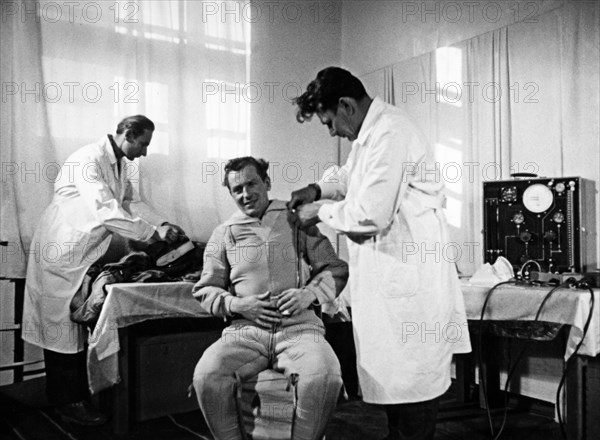 Soviet cosmonaut gherman titov being helped in the putting on of his space suit in preparation for his flight in the vostok 2 mission, 1961, a still from the documentary film 'to the stars again'.