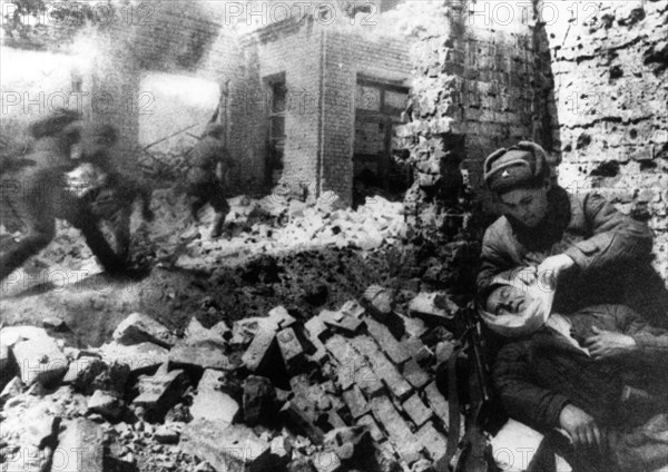 Nurse bandaging a wounded soldier during street fighting in stalingrad, december 1942.