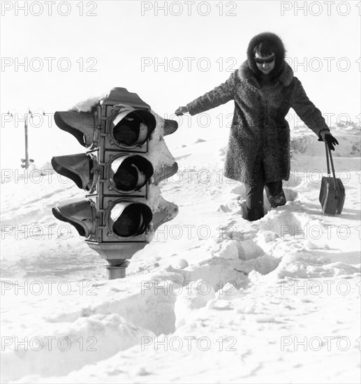 A woman walking by a traffic light on a huge snow drift after a five-day blizzard in yuzhno-sakhalinsk in the southern part of the soviet island of sakhalin, february 1970.