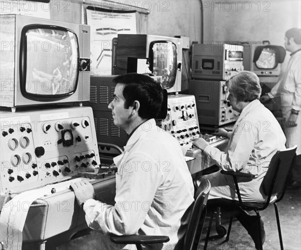 Soviet health resorts, doctors of the lermontov sanatorium in odessa, ukraine, on the black sea coast, observing patients during treatments, a patient in the sanatorium's swimming pool can be seen on the screen in the foreground while his heart rate is being monitored, january 1973.