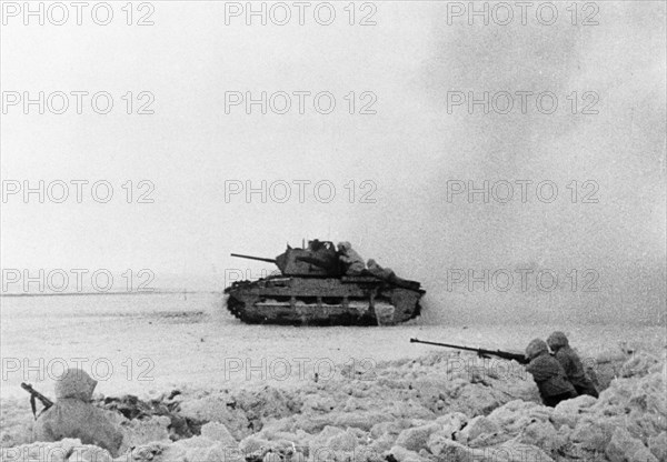 A british tank manned by red army soldiers advancing on the enemy during world war 2, an anti-tank rifle crew is in the trench (right).