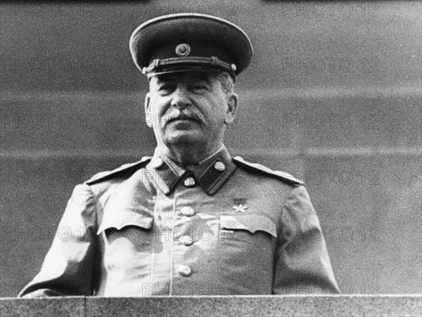 Joseph stalin standing on lenin's tomb in red square, reviewing the may day parade in 1952.