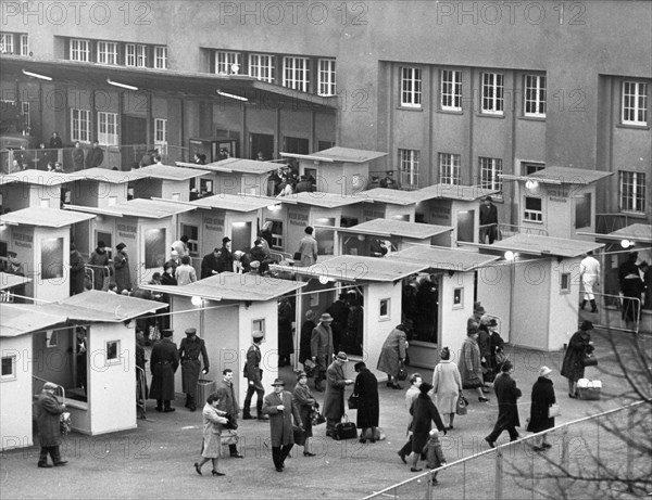 West berliners crossing over to visit relatives in east berlin in accordance with a recently signed treaty allowing such visits, october 1964, pictured are the customs booths at the friedrich strasse checkpoint set up specifically to handle the traffic.