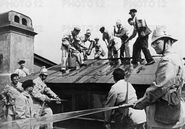 world war ll, composer dmitri shostakovich (right), member of the volunteer fire fighting squad of the leningrad conservatory, during a drill in which he and the other teachers learn to handle incendiary bombs.