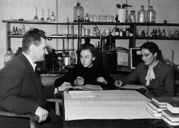 Professor dr, antoni basinski, chairman of the faculty of physical chemistry at the mikolaj kopernik university in torun, poland, giving an exam to maria kaliska and krystyna kedzierska, two graduate students in the field of engineering chemistry, may 1954.