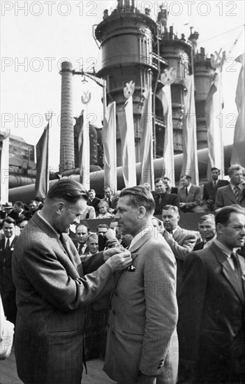 Piotr jaroszewicz, vice-chairman of the polish council of ministers, decorating engineer kiersnowski with the 'standard of labor' medal during the celebration of the opening of the big furnace at the lenin steel works in nowa huta, poland, july 21, 1954.