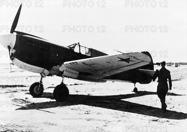 A russian pilot about to enter an american fighter plane (p-41?) that was just delivered, complete with red star insignia, to the red air force at an assembly center for u,s, lend-lease aircraft in iran.