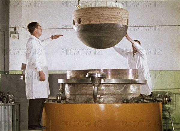 The descent capsule of the soviet space probe venera 5 or 6 being lowered into an installation for testing heat resistance, 1968, this is a still from the film 'the storming of venus', produced by e, kuzis at the tsentrnauchfilm central scientific film studio, released on may 17, 1969.