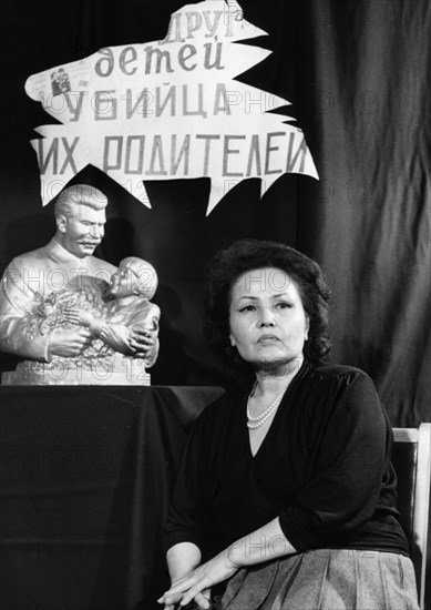 Engelsina cheshkova (gelya markizova) at a conference in 1990, behind her is one of the ubiquitous statues from 1936 of her as a 7-year-old with stalin and a sign that reads: 'friend of children, murderer of their parents'.