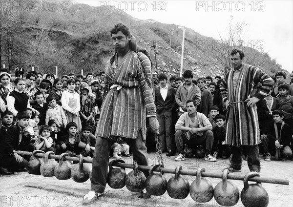 Tajik schoolteacher khamid mirzoev taking part in a weight-lifting contest during a sports festival at the chorbog state farm in the leninsky district of the tajik ssr, these autumn festivals are held to celebrate the end of the cotton harvesting season, 1990.