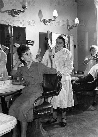 Hairdresser maria belyayeva has just done the hair of z, avkhimkova who works at an odezhda ready-made clothes store on frunze embankment, moscow, ussr, 1957.