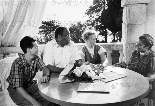 Paul robeson and his wife eslanda during a visit to a summer resort in sochi, august 1958,  they are sitting on the veranda of the 'new sochi' sanitorium with their guests adoi korotkevich, a tashkent schoolgirl, and a moscow student andrei stochin.