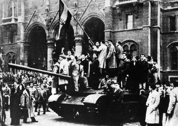 Hungarian uprising, jubilant insurgents outside the hungarian parliament building waving the national hungarian flag from an hungarian army tank in budapest, hungary, october 1956.