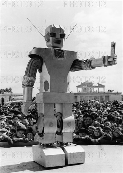 A 'robot' holding a copy of the soviet newspaper pravda, designed by youthful muscovites, kindly inviting visitors into the 'ussr electrification' pavilion of the ussr economic achievements exhibition in moscow, ussr, june 1959.