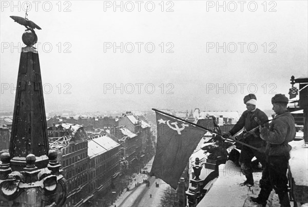 World war 2, soviet soldiers raising the flag of victory above a city building in budapest, hungary after the capture of the hungarian capital, february 1945.