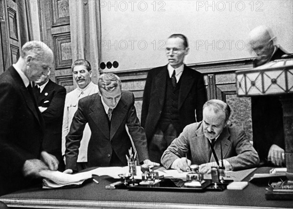 Vyacheslav molotov, chairman of the people's commissars' council and people's commissar for foreign affairs, signing of the treaty of non-aggression between germany and the union of soviet socialist republics on august 23, 1939, in the background is joseph stalin.