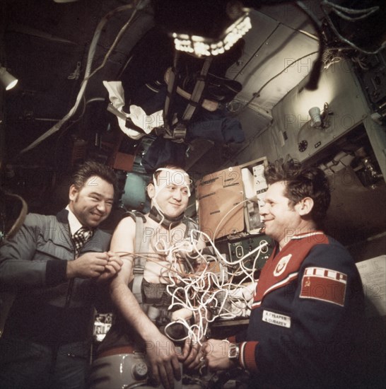 Soviet cosmonauts georgi grechko and alexei gubarev performing a medical experiment on vladimir remek aboard the salyut 6 space station, soyuz 26 and soyuz 28, 1978.
