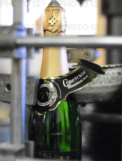 Moscow, russia, november 29, 2010, a label being applied to a bottle of sovetskoye shampanskoye on a bottling line at kornet, a moscow-based champagne winery.