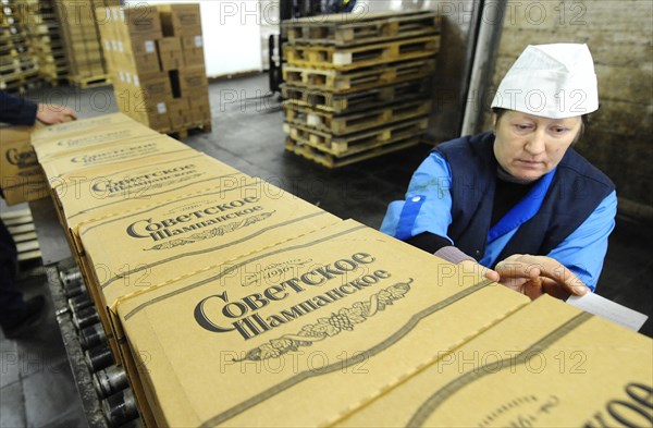 Moscow, russia, november 29, 2010, worker sticks labels on boxes of bottles of sovetskoye shampanskoye at kornet, a moscow-based champagne winery.