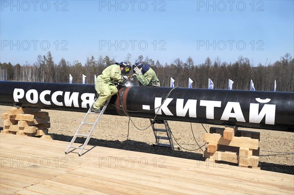 Amur region, russia, april 27, 2009, workers welding the first segment of a branch pipeline which will run into china from the eastern siberia – pacific ocean (espo) oil pipeline, the slogan on the pipeline reads: russia - china.