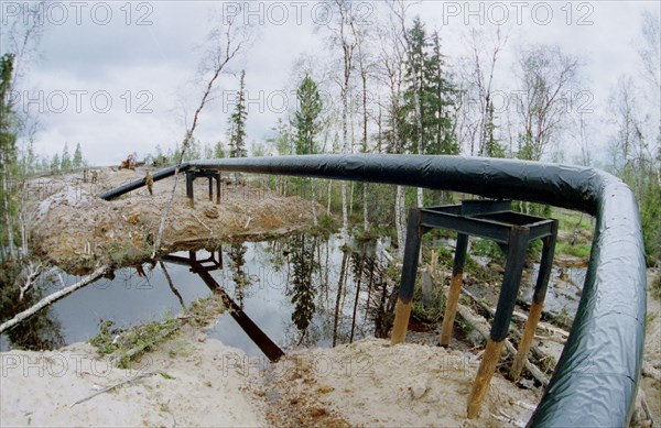 The tyumen area, 1995, the sugmut deposit located among bogs between of nadym and purya, is one of the largest on stocks of oil in western siberia, in a picture: an oil pipeline from the sugmut deposits, pipes go not on a river bed, and above it, on both coast are established the cranes, allowing to stop submission of oil in case of failure, it is made for prevention of ecological accidents, alexey shchukin's photo.