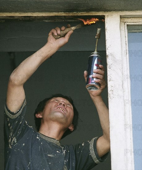 A north korean guest worker repairs a window, in vladivostok, russia, january 28 2003,russian businessmen like to hire foreign citizens (chinese, vietnamese, north koreans) who agree to work under any unfavourable conditions, the administration of russia's maritime territory decided to hire over 500 guest workers in the current year, basically to be employed for low paying manual jobs.