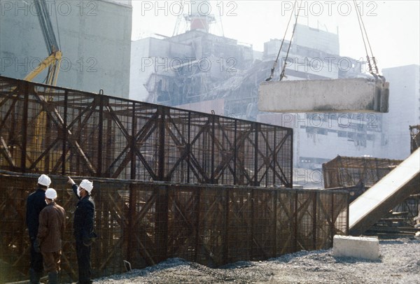 Construction crews building a containment wall around the damaged unit 4 reactor, chernobyl aps, ukraine, ussr, august 1986.