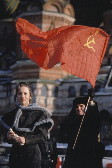 A young woman with a man carrying a soviet hammer and sickle flag during an anti-government demonstration in red square, early 1990s.