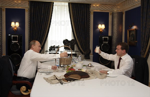 Moscow region, russia, october 1, 2010, president of russia dmitry medvedev (r) and prime minister vladimir putin raise glasses with a sour milk drink (from the ruzskoye moloko dairy company) while having a snack together during their meeting at gorki residence.