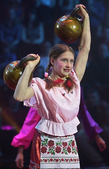 Russian strong woman lifting heavy kettle bell weights.