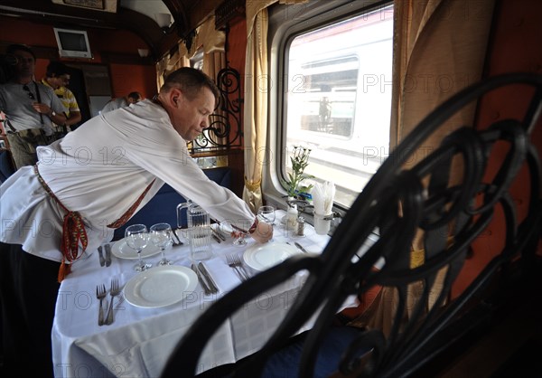 Moscow, russia, august 16, 2011, waiter in traditional russian costume lays the table in a diner car on a moscow-to-beijing passenger train