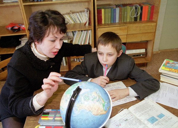 Novosibirsk,russia, january 30, 2001, picture shows a teacher marina gurgutsa explaining geography to her pupil valera savchenko in a classroom of a new orphanage opened recently in akademgorodok (the town of scientists of the siberian academy of sciences) near the city of novosibirsk, about 20 children from 5 to 16 years of age who are in great need of social rehabilitation and assistance found their shelter there.