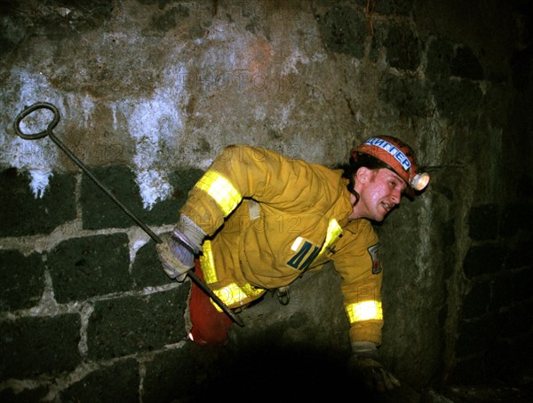 A member of the 'diggers of the underground planet' club busy with a research of the municipial underground space on their own initiative pictured 'breaking through' a wall while inspecting caveries which may cause a collapse in a densely populated area of the city, they used to observe old underground communication lines which are in a dangerous plight and may be a reason for an accident, moscow, russia, october 13, 1999.