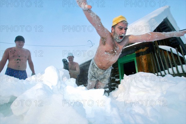 A man diving into the snow after a steam bath at a banya in a village in the ivanovo region of russia, it is a tradition of the winter russian banya (sauna), 2006.