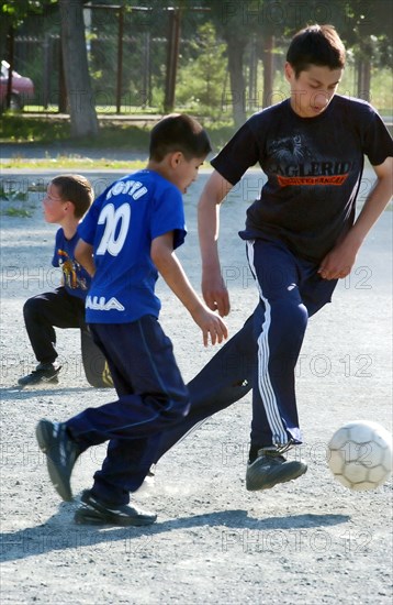 Teenagers play football in a chelyabinsk yard, russia, august 2006.