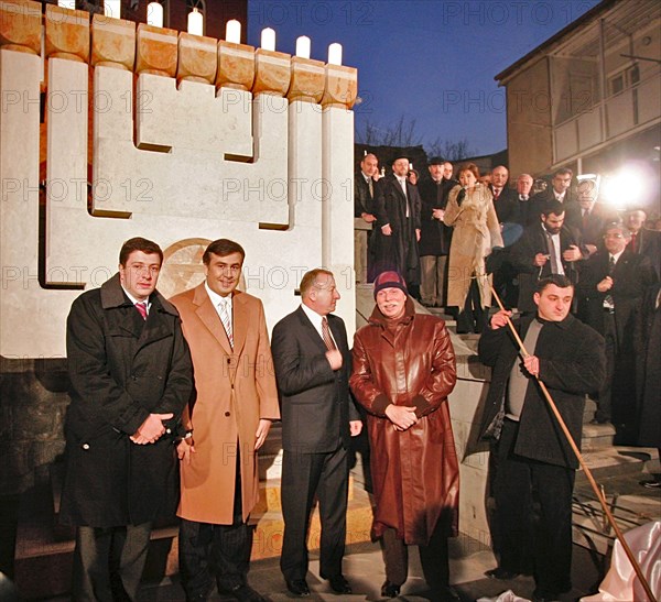 Tbilisi, georgia, december 18, 2006, tbilisi mayor gigi ugulava, georgian president mikhail saakashvili, israeli ambassador to georgia shabtai tsur and president of the georgian national olympic committee, business tycoon badri patarkatsishvili, l-r, attend the hanukkah celebration outside the cityi´s synagogue, pictured in the background is a hanukkah menorah.