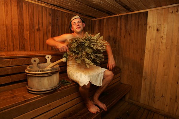 A man rubbing himself with a birch branch at a banya (sauna) at the pushkarskaya sloboda hotel in russia.