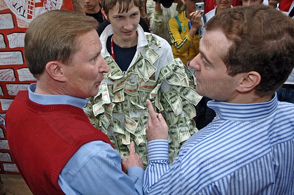 Russia's first deputy pms sergei ivanov and dmitry medvedev, l-r, look at each other as a man wearing dollar bills stands nearby at the summer camp of the pro-putin nashi (our people) youth movement at the lake seliger resort, tver region, russia, july 21, 2007.