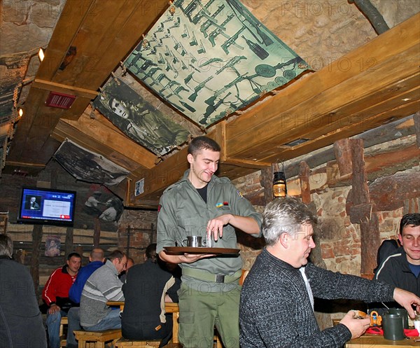 Waiter serving drinks at kryivka, a new cafe with the decor of a upa (ukrainian insurgent army) bunker, in the city of lvov (lviv), western ukraine, october 2007.