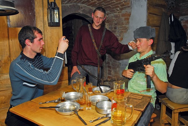 Young people with an assault rifle and an empty ammo belt pose for a photograph at kryivka, a new cafe with the decor of a upa (ukrainian insurgent army) bunker, in the city of lvov (lviv), western ukraine, october 2007.