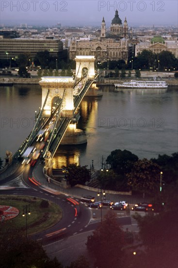 The chain bridge across the dunabe in budapest, hungary looking towards gresham palace, it was constructed in the middle of the 19th century and was the first permanent connection between buda and pest, the bridge was destroyed during world war ll and rebuilt in its original form by 1949.